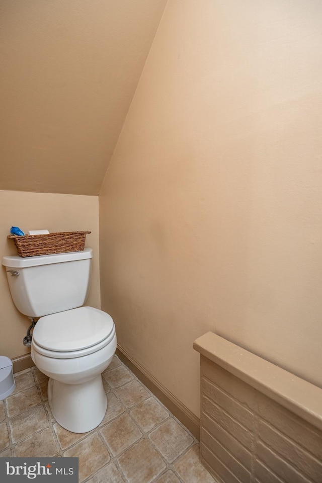 bathroom featuring baseboards, toilet, and lofted ceiling