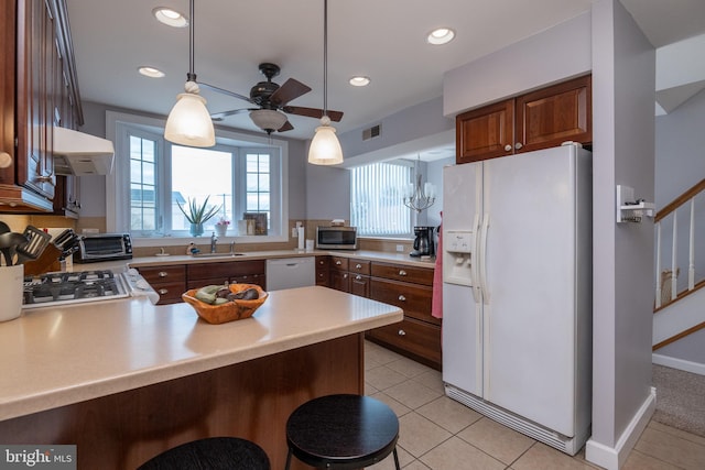 kitchen featuring white appliances, a peninsula, a sink, light countertops, and under cabinet range hood