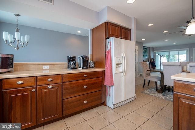 kitchen featuring light tile patterned floors, stainless steel microwave, light countertops, and white fridge with ice dispenser