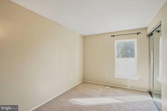 unfurnished room with visible vents, baseboards, and light colored carpet