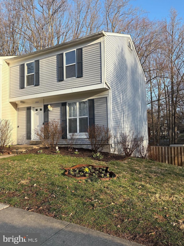 colonial-style house featuring a front lawn and fence