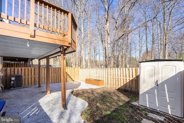 view of yard with an outbuilding, a fenced backyard, a shed, central AC unit, and a patio area