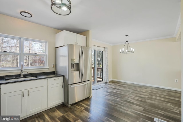 kitchen with a sink, dark countertops, dark wood finished floors, white cabinetry, and stainless steel fridge