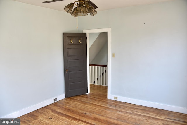 spare room with baseboards, wood finished floors, and a ceiling fan