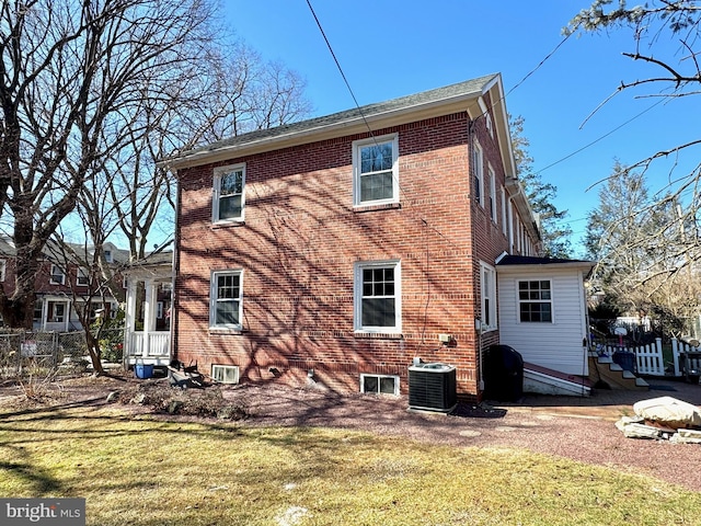 back of property with a yard, central AC unit, and brick siding