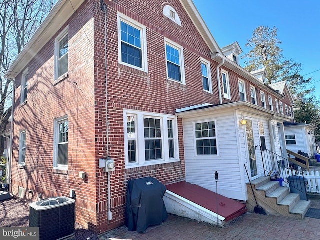 view of side of home with central air condition unit, brick siding, and entry steps