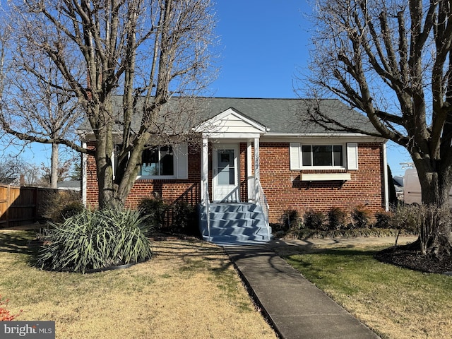 bungalow with a front yard, fence, and brick siding