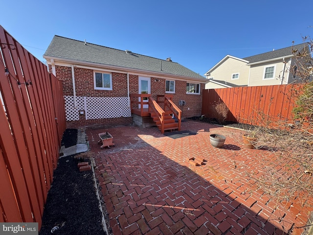 back of house with a patio, fence, brick siding, and roof with shingles