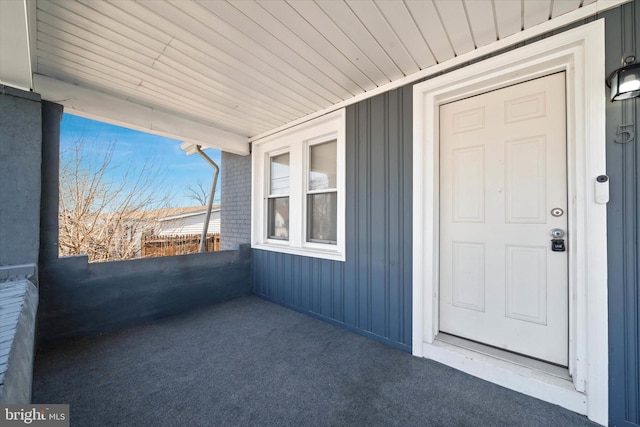 doorway to property featuring brick siding, board and batten siding, and a porch