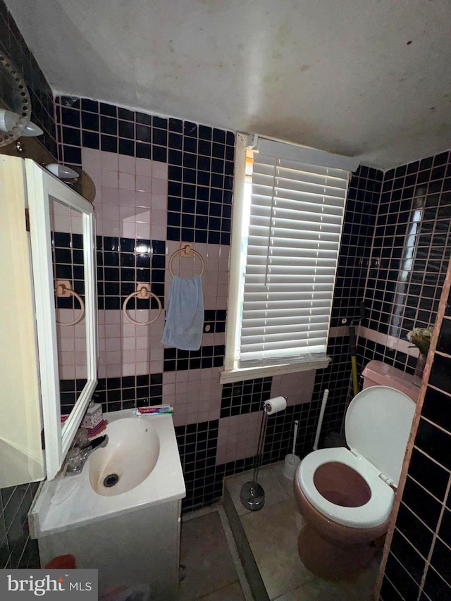 bathroom with toilet, tile walls, vanity, and tile patterned flooring