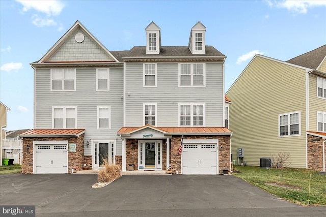 multi unit property featuring a standing seam roof, driveway, and a garage