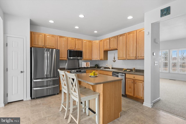 kitchen with a sink, a kitchen island, dark countertops, recessed lighting, and stainless steel appliances