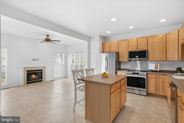 kitchen featuring a kitchen island, recessed lighting, appliances with stainless steel finishes, a kitchen bar, and dark countertops