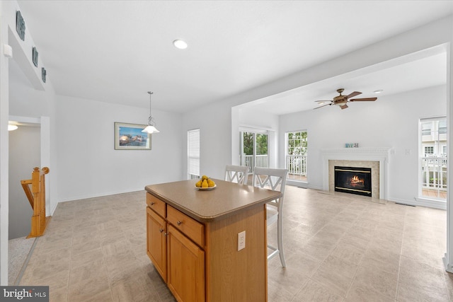 kitchen featuring baseboards, a kitchen island, a breakfast bar, ceiling fan, and hanging light fixtures