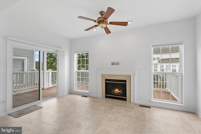 unfurnished living room featuring a high end fireplace, visible vents, baseboards, and ceiling fan