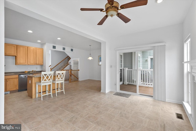 kitchen featuring visible vents, a breakfast bar, a ceiling fan, a kitchen island, and dishwasher