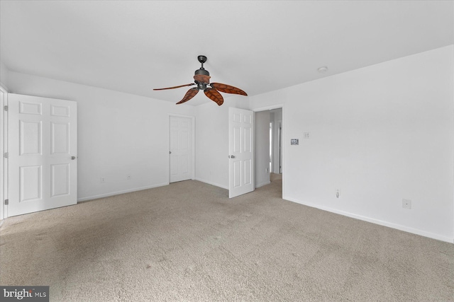 unfurnished room featuring a ceiling fan, light colored carpet, and baseboards