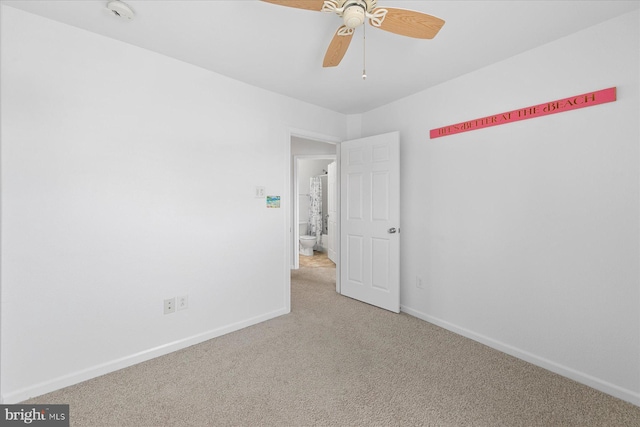 carpeted spare room featuring baseboards and a ceiling fan