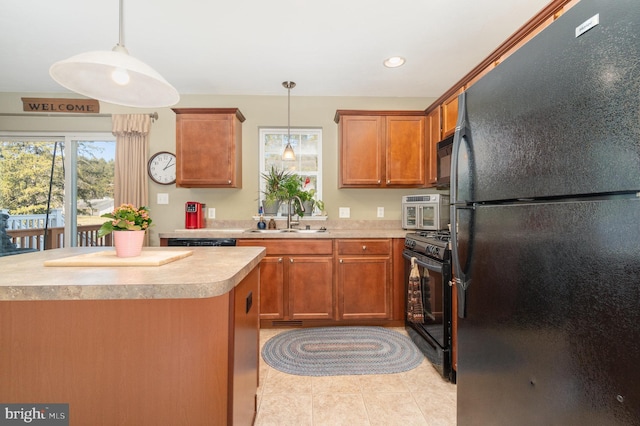 kitchen with pendant lighting, light countertops, light tile patterned floors, black appliances, and a sink