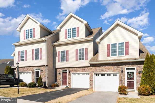 townhome / multi-family property featuring stone siding, a garage, driveway, and a shingled roof