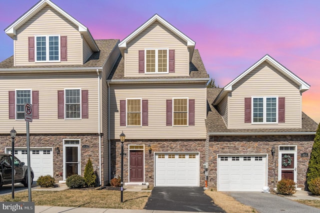 view of front facade with a garage, stone siding, and driveway