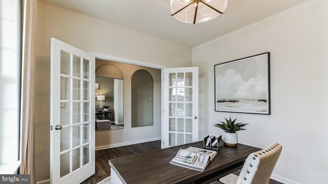 office space with dark wood-style floors, french doors, arched walkways, an inviting chandelier, and baseboards