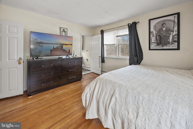 bedroom featuring a baseboard heating unit and light wood finished floors