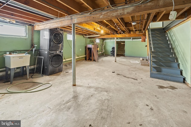below grade area featuring stacked washer and clothes dryer, stairs, and a sink