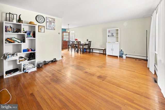 interior space with light wood-style flooring, visible vents, and a baseboard radiator