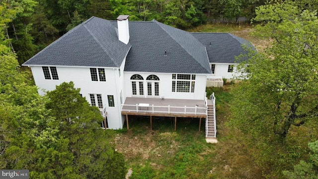 rear view of house with a wooden deck, roof with shingles, a chimney, and stairs