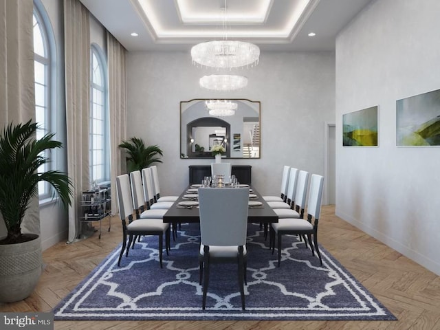 dining space with a notable chandelier, a raised ceiling, a high ceiling, and baseboards