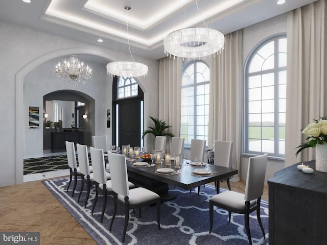 dining area featuring arched walkways, a healthy amount of sunlight, a raised ceiling, and a high ceiling