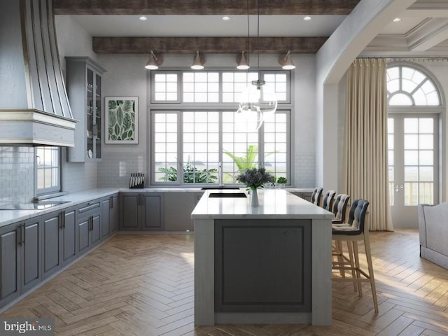 kitchen featuring black electric cooktop, gray cabinetry, a center island, and light countertops