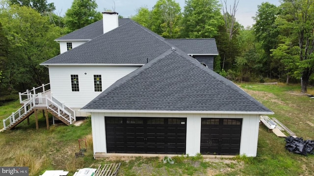 rear view of property featuring stairway, a chimney, and roof with shingles