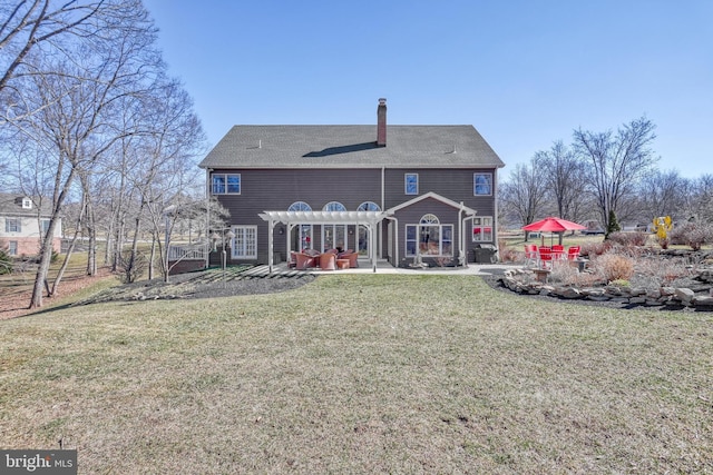 rear view of property featuring a chimney, a patio area, a pergola, and a lawn