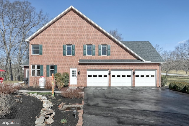 view of front of home with a garage, brick siding, roof with shingles, and driveway