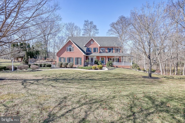 view of front of house with brick siding, covered porch, and a front lawn