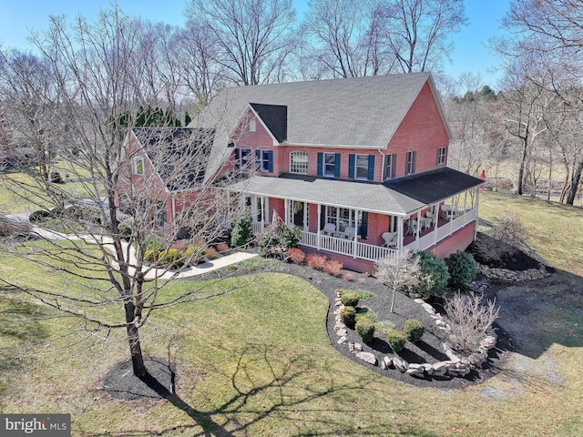 view of front facade featuring brick siding, a porch, and a front lawn