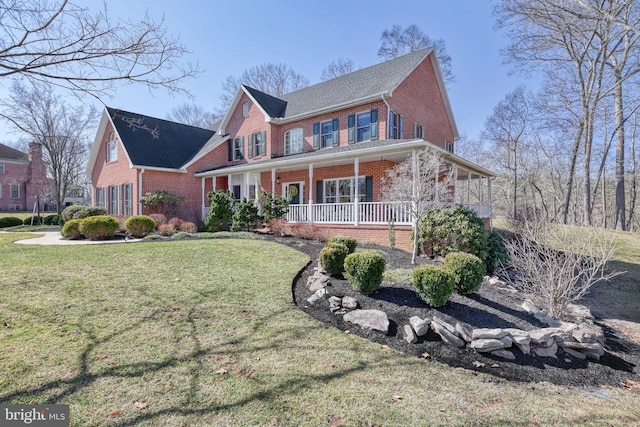 view of front of property featuring brick siding, a porch, and a front yard