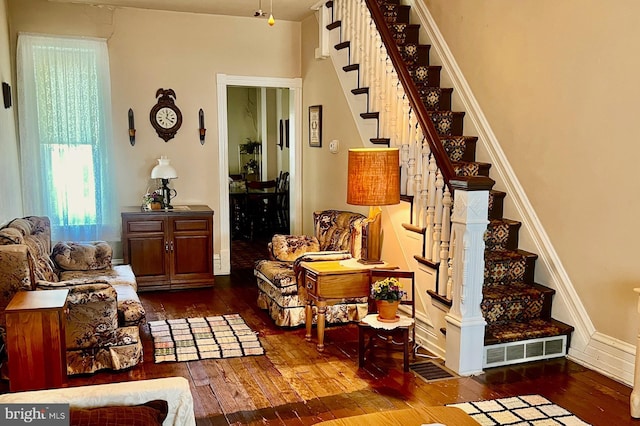 living area with visible vents, stairway, and hardwood / wood-style flooring