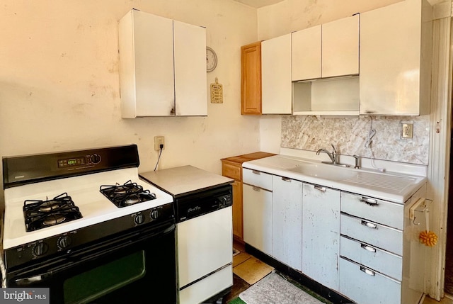 kitchen featuring dishwasher, light countertops, range with gas stovetop, decorative backsplash, and a sink