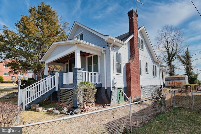 view of front of home with stairs, a porch, fence, and a chimney