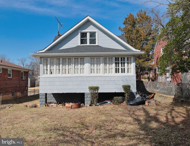 view of front of home with a front yard, fence, and roof with shingles