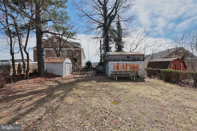 view of yard featuring a storage unit, an outdoor structure, and fence