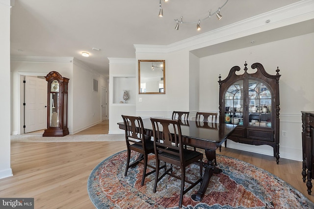 dining space featuring visible vents, light wood-style flooring, rail lighting, and ornamental molding