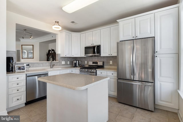 kitchen with backsplash, white cabinets, stainless steel appliances, and a sink