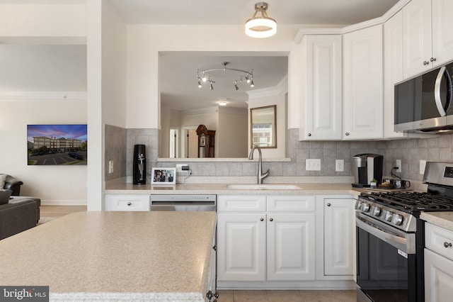 kitchen featuring tasteful backsplash, light countertops, appliances with stainless steel finishes, white cabinets, and a sink