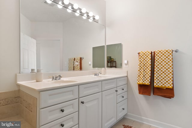 bathroom featuring tile patterned flooring, double vanity, visible vents, and a sink