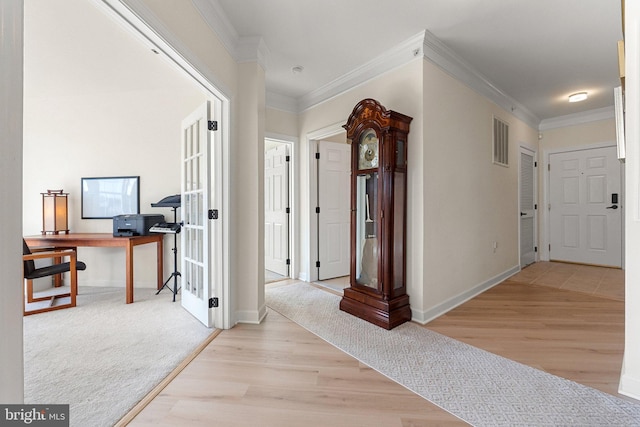 hall featuring light wood-type flooring, visible vents, and ornamental molding