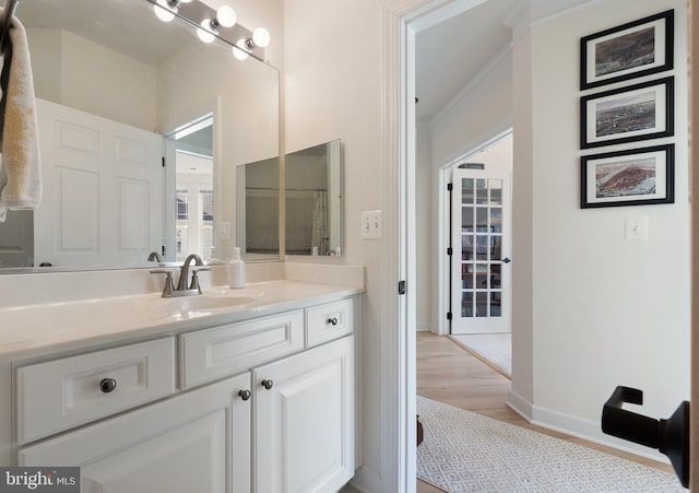 bathroom with vanity, crown molding, wood finished floors, and baseboards